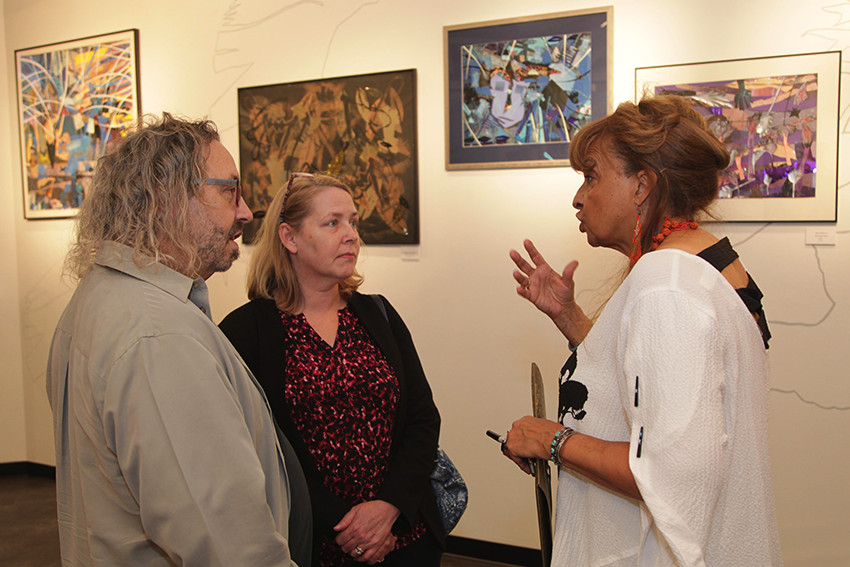 Robin Chandler talking with two visitors in the art gallery