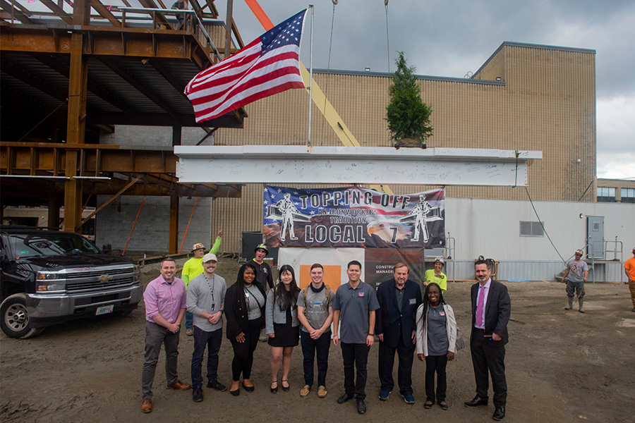 faculty, staff and students in front of the final structural beam
