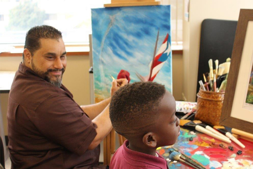 artist painting at an easel with a child next to him