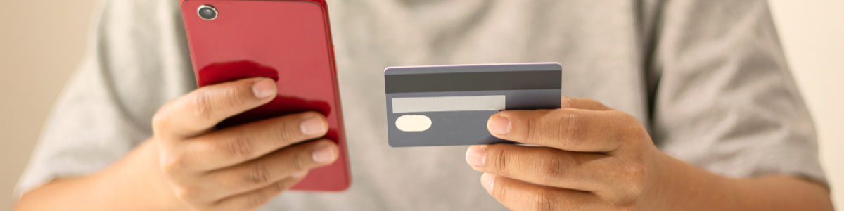 Person holding a credit card and phone A man looking at a phone